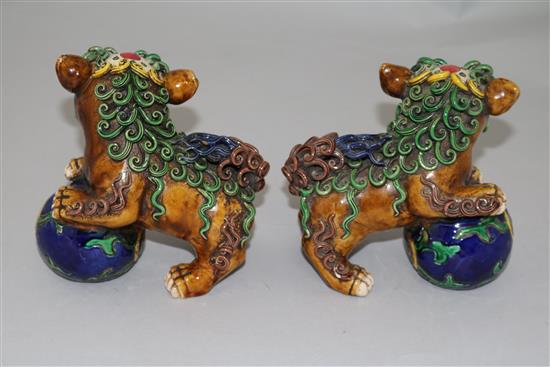 A pair of Chinese polychrome pottery figures of lion-dogs with balls, height 12cm